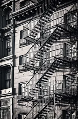Zelfklevend Fotobehang Outside metal fire escape stairs, New York City, black and white © Delphotostock