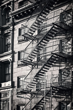 Fototapeta Outside metal fire escape stairs, New York City, black and white