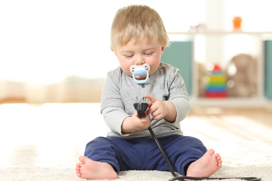 Baby in danger playing with an electric plug