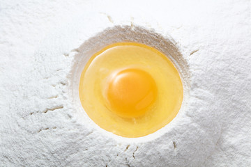 raw liquid egg on top of the heap of wheet flour