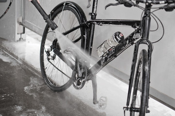 Fototapeta na wymiar Man washing the bike with a strong jet of water. Washing the bike after the trip.