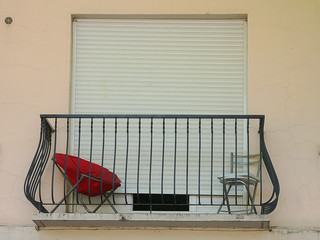 Bright red chair on a closed up apartment balcony, rural France