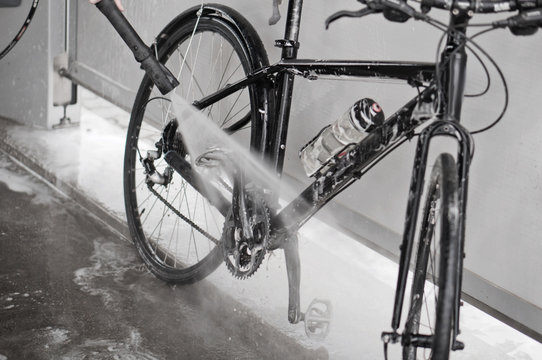 Fototapeta Man washing the bike with a strong jet of water. Washing the bike after the trip.