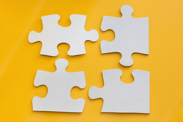 Four disconnected jigsaw puzzle pieces on yellow background. Concept of finding right solutions in...