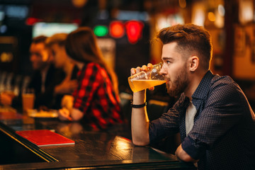 Man drinks beer at the bar counter in a sport pub