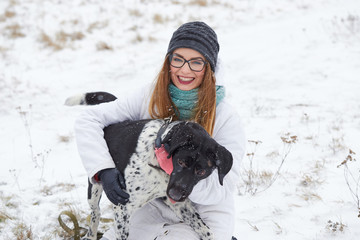 a dog pointer walks a girl in winter.