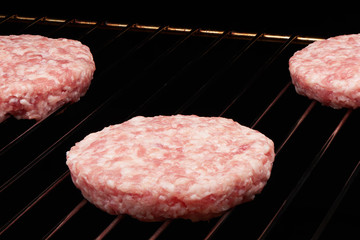 Raw hamburgers cooking on grill