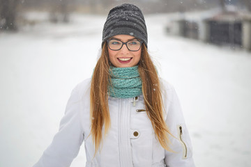 Obraz premium portrait of a cheerful girl with glasses in a snowfall in winter.