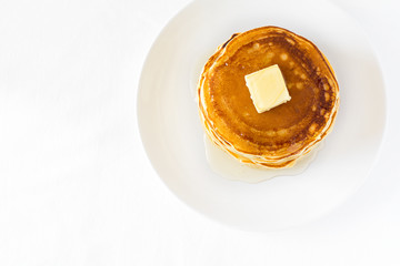 Stack of pancakes with butter and honey on white background