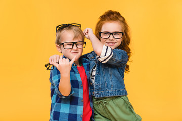 portrait of smiling kids in eyeglasses isolated on yellow - obrazy, fototapety, plakaty