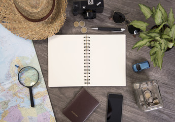 note book and world map for planning vacation with other travel accessories around.