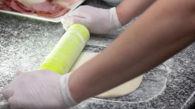 Hands shaping pizza crust. Dough, flour and rolling pin.