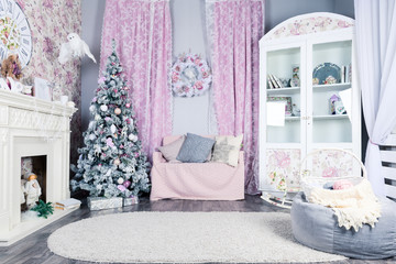 Beautiful Christmas interior design. Pink room with white fireplace, decorated Christmas tree, sofa with soft pillows and soft carpet. Concept of New Year, celebration and holiday