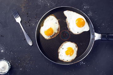 Preparation of fried eggs. Frying pan on a black background