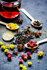 Teacup and herbs on dark stone background