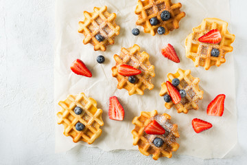 Waffles with stawberries and blueberries border on paper, grey background