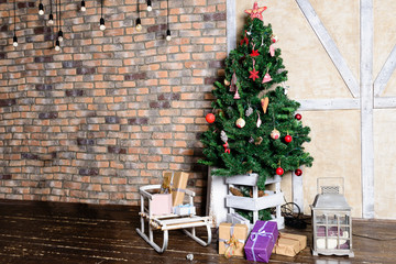 Beautiful Christmas interior design. In the room decorated Christmas tree with gift under it, sled and small lamps. Concept of Merry Christmas, winter and New Year