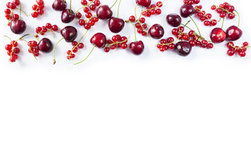 Red food at border of image with copy space for text. Ripe cherries and red currants on a white background. Red berries and fruits. Various fresh summer berries on white background. Top view.