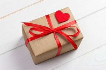 Valentines day background. Red heart, ribbon, and gift box on wooden background