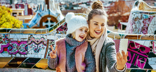 Fototapeta premium smiling mother and daughter tourists taking selfie in Barcelona