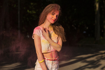 Naklejka premium Cool young woman posing covered with yellow and pink Holi paint