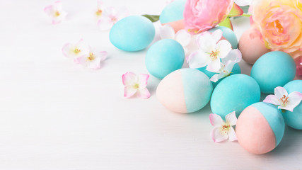 Fototapeta na wymiar Easter and flowers background, spring concept. Blue and pink chicken eggs on white wooden table, pastel colors