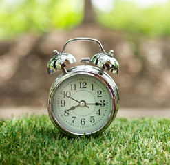 Retro alarm clock on green grass. time concept