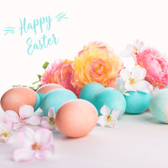 Easter and flowers background, spring concept. Blue and pink chicken eggs on white wooden table, pastel colors