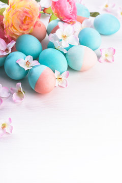 Easter and flowers background, spring concept. Blue and pink chicken eggs on white wooden table, pastel colors