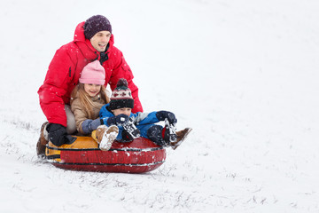 Fototapeta na wymiar Picture of happy father, daughter and son on tubing in winter park