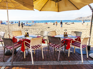 Las-Palmas de Gran Canaria, Spain, on January 5, 2018. Little tables of street cafe on the embankment near the Playa de Las Canteras beach expect visitors