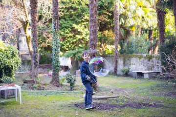 7-year-old child outdoors in the garden in winter makes big soap bubbles