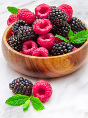 Wooden cup with fresh berries on marble table 