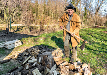 Senior man splitting wood with ax in the garden.