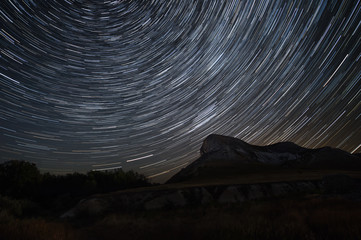 Beautiful star trails time-lapse over the hills. Polar Star at the center of rotation.Lateral light...