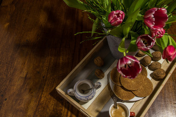 Traditional syrup waffles, dutch tulips, walnuts, sugar pot and coffee on a wooden serving tray
