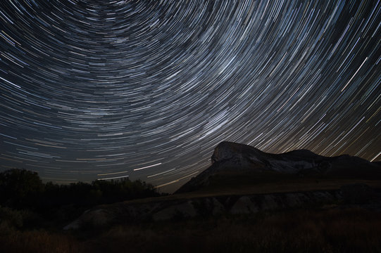 Beautiful star trails time-lapse over the hills. Polar Star at the center of rotation.Lateral light from the full moon on the chalk hills. 