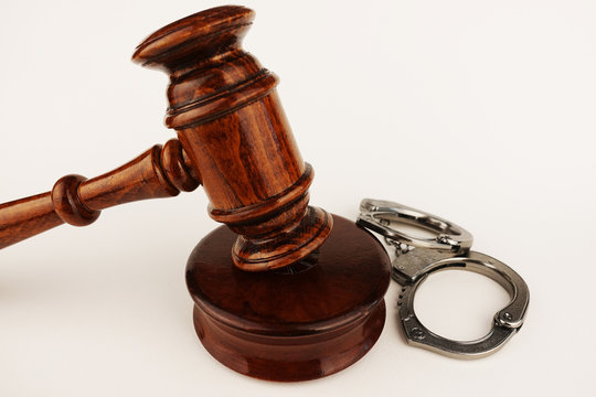 Justice or legal law concept with judge hammer and handcuffs on white background