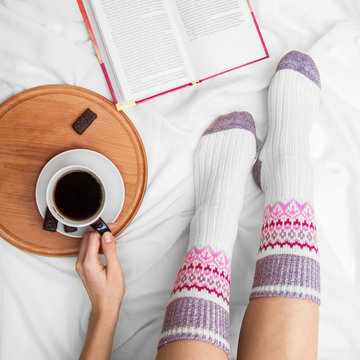 Girl on the bed with an old book and a cup of coffee, top view