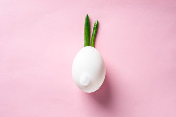 Egg shell and feathers green onion imitation rabbit, bunny on pink colored paper background. Food concept minimal Easter - 189180348