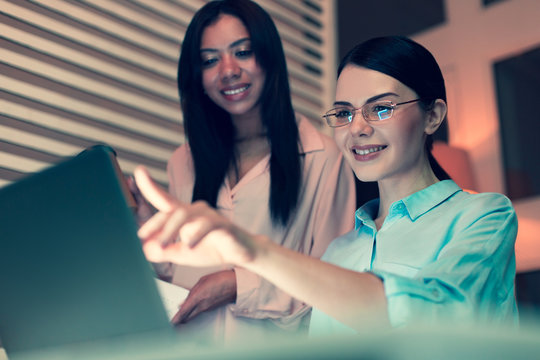 Comprehensive Report. Beautiful Young Woman Pointing At The Laptop Screen And Telling Her Female Boss About The Current Work Progress