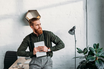 businessman holding tablet and looking away