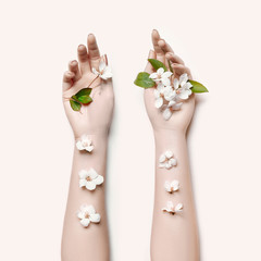 Fashion art hand woman in summer time and flowers on her hand with bright contrasting makeup. Creative beauty photo hand girls sitting at table on contrasting background with colored shadows. Skincare