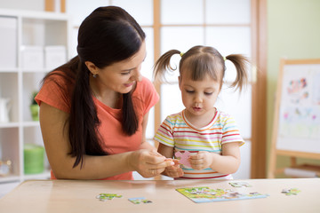 Attentive mom giving child a puzzle piece