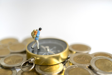 Miniature toy:Young hipster tourist planning saving money for tour on compass and coins : tour ,saving money ,adventure concept.