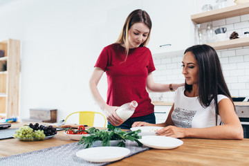 Woman pour milk into bowl her friend in kitchen