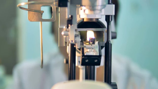 A patients POV on an ophthalmological slit lamp with a doctor in the background. 4K.