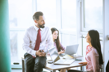 Team lead sitting on table next to manager. Office concept.