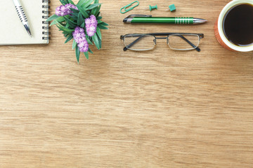Top view aerial image shot of arrangement accessory business background concept.Flat lay black coffee & essential items pen and notebook with plant in pot on modern wooden table at home office desk.