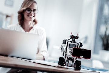 Modern technologies. Positive delighted female person smiling while looking at her invention,...